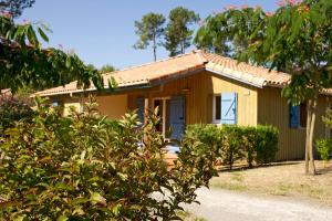 een klein geel huis met een boom bij Village Vacances Le Lac Marin in Soustons