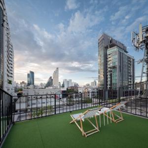 a balcony with a green floor and two chairs on it at The BoB Hostel in Bangkok