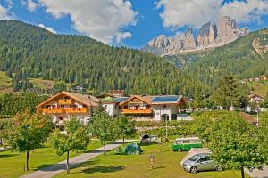 a village with cars parked in front of a mountain at Cesa Melester in Campitello di Fassa