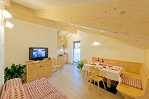 a living room with a dining table and a television at Cesa Melester in Campitello di Fassa