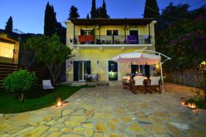 a house with a patio with a table and an umbrella at Taxi Driver Apartments in Paleokastritsa