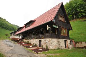 a building with a red roof on a hill at Penzión Pastierňa in Dedinky