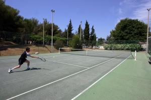 un hombre jugando al tenis en una pista de tenis en Village Vacances La Manne en Bormes-les-Mimosas