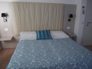a bedroom with a bed with a blue and white blanket at Hotel Lucerna in Castiglione della Pescaia