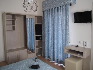 a living room with blue curtains and a tv at Hotel Lucerna in Castiglione della Pescaia