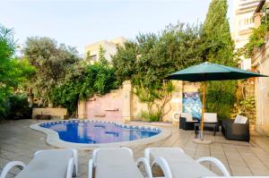 a pool with white chairs and an umbrella at Il-Wileġ Bed & Breakfast in Qala
