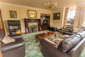 a living room with leather couches and a fireplace at Cloghan Lodge in Castleisland