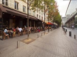 an empty street with people sitting at tables and chairs at Sourdiere Louvre Vendome in Paris