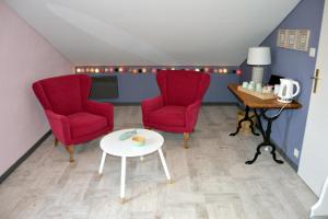 a living room with two red chairs and a table at Le Bon Etage in Fresnes-en-Woëvre