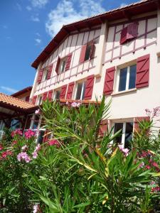 タルノスにあるVillage Vacances La Forêt des Landesの赤い窓と花が目の前に咲く建物