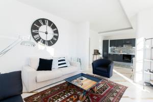 a living room with a white couch and a clock on the wall at Sunset House La Terrazza in Assisi