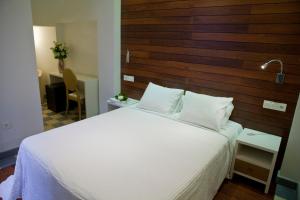 a bedroom with a white bed with a wooden headboard at Hostal El Alojado de Velarde in Conil de la Frontera