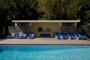 a group of blue lounge chairs next to a pool at Casa de Pedra in Ribeira Quente