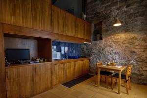 a kitchen with wooden cabinets and a table with a television at Casa de Pedra in Ribeira Quente