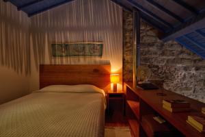 a bedroom with a bed and a table with a lamp at Casa de Pedra in Ribeira Quente