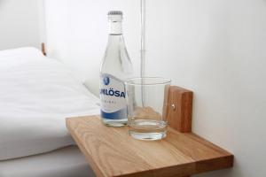 una botella de agua y un vaso sobre una mesa de madera en Flygplatshotellet en Landvetter