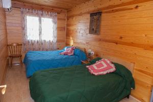 two beds in a cabin with wooden walls at Casa Rural los Caños in Fuente-Álamo