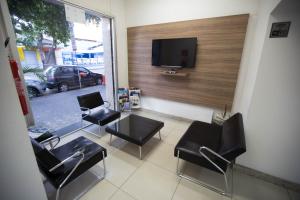 a room with chairs and a table and a tv at Hotel Oitis in Governador Valadares