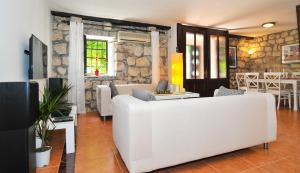a living room with a white couch and a stone wall at Holiday Home Maris in Kotor