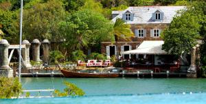 a boat on the water in front of a house at Admiral's Inn and Gunpowder Suites in English Harbour Town