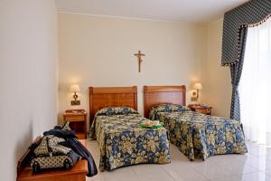 a bedroom with two beds and a cross on the wall at Hotel Centro di Spiritualità Padre Pio in San Giovanni Rotondo