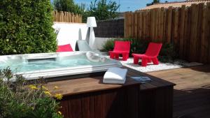 a hot tub in a yard with red chairs and a fence at Logis Hôtel La Chaize in Noirmoutier-en-l'lle