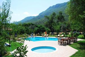 a swimming pool with tables and chairs next to a mountain at Doga Apartments in Kayakoy