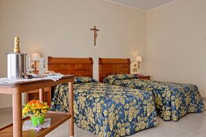 a bedroom with two beds and a cross on the wall at Hotel Centro di Spiritualità Padre Pio in San Giovanni Rotondo