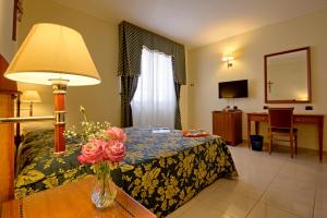 a hotel room with a bed and a table with a vase of flowers at Hotel Centro di Spiritualità Padre Pio in San Giovanni Rotondo