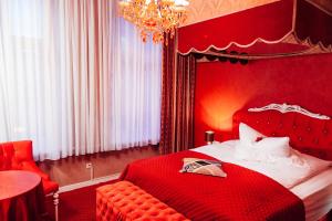 a red bedroom with a bed and a chandelier at Hotel Village in Hamburg