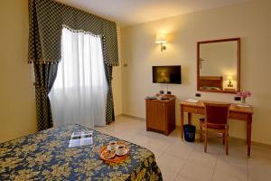 a hotel room with a bed and a desk and a mirror at Hotel Centro di Spiritualità Padre Pio in San Giovanni Rotondo