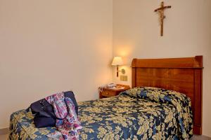 a bedroom with a bed and a cross on the wall at Hotel Centro di Spiritualità Padre Pio in San Giovanni Rotondo