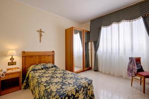 a bedroom with a bed and a cross on the wall at Hotel Centro di Spiritualità Padre Pio in San Giovanni Rotondo