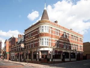 ein großes Backsteingebäude mit einem Kirchturm auf einer Straße in der Unterkunft The Brewers Inn in London