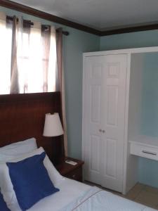 a bedroom with a bed with a blue pillow and a window at Believe Caribbean Apartment in Bridgetown
