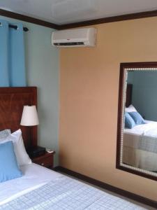 a hotel room with a bed and a mirror at Believe Caribbean Apartment in Bridgetown