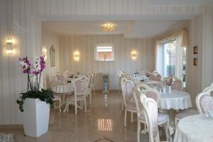 Hotel Gode Wind في كيل: غرفة طعام مع طاولات بيضاء وكراسي وزهور