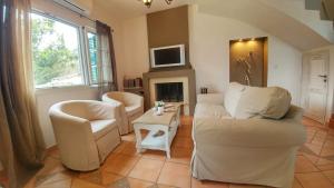 a living room with two chairs and a fireplace at Villa Del Sol in Asprogerakata