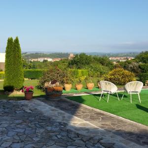deux chaises blanches et des plantes en pot sur une pelouse dans l'établissement Alojamientos el Paramo, à San Vicente de la Barquera