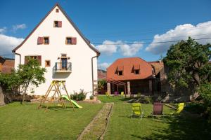 una casa con parque infantil y sillas en el patio en La Maison d'Emilie, en Pfaffenheim