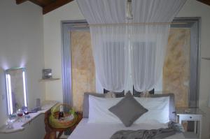 a bedroom with a bed with white curtains and a desk at Villa Suites Lagonisi Luxury in Lagonissi