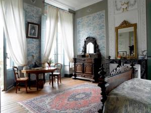 1 dormitorio con cama, mesa y espejo en Chambres d'Hôtes du Chateau de Saint Sulpice, en La Sauvetat-sur-Lède