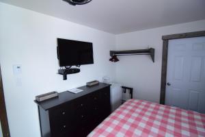 a bedroom with a bed and a tv on the wall at Mon Coin de Pays in Sacré-Coeur-Saguenay