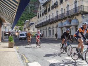 a group of people riding bikes down a city street at Hôtel Les Templiers in Luz-Saint-Sauveur