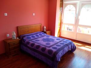 a bedroom with a purple bed and a window at Albergue de Peregrinos La Espiral in Finisterre