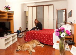 a woman sitting on a bed with a dog laying on the floor at Hotel Helvetia in Genoa