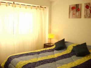 1 dormitorio con 1 cama con manta amarilla y azul en Rent Apart Caballito 3 en Buenos Aires