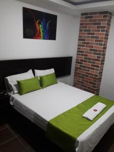1 cama con sábanas verdes y blancas y pared de ladrillo en Hotel Valle de Beraca en Cúcuta