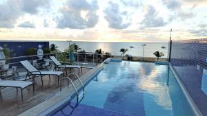 uma piscina no topo de um edifício com o oceano em Apartamento Tambau a Beira Mar em João Pessoa