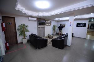 a man standing in a lobby with two black leather couches at Hotel Leon in Barbalha